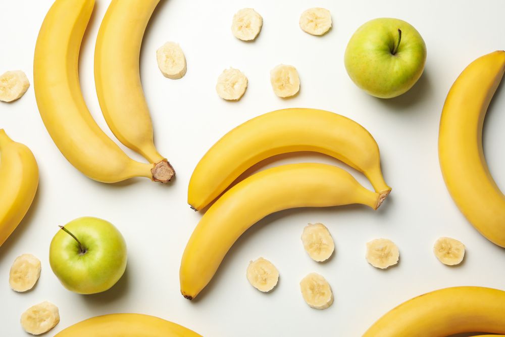 Bananas and apples on light background, top view. Fresh fruit