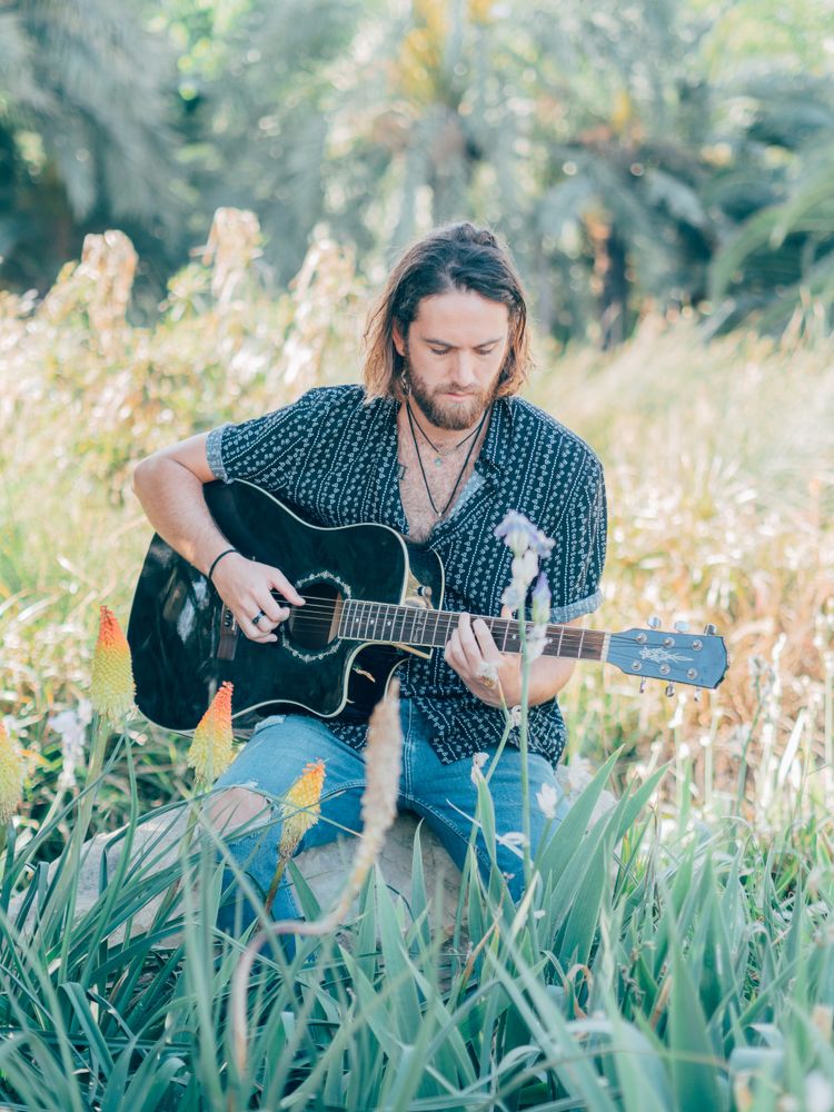 Hipster man in meadow with guitar