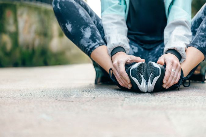 Woman stretching legs while sitting on the floor holding her feet