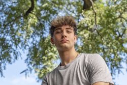 Low angle of a young man, serious, looking at the camera in a pu