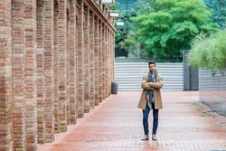 Portrait of young man with arms crossed standing on brick road