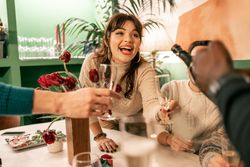 Young woman laughing joyfully during a Christmas toast with diverse friends.