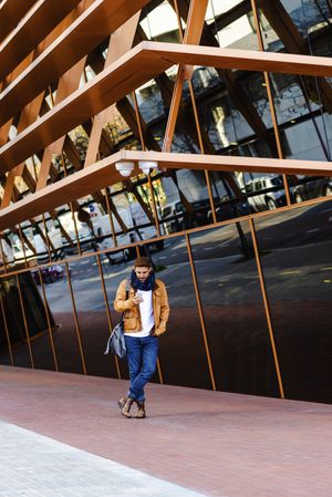 Stylish guy using smartphone outside modern building
