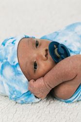 Newborn baby wrapped on soft blanket with pacifier