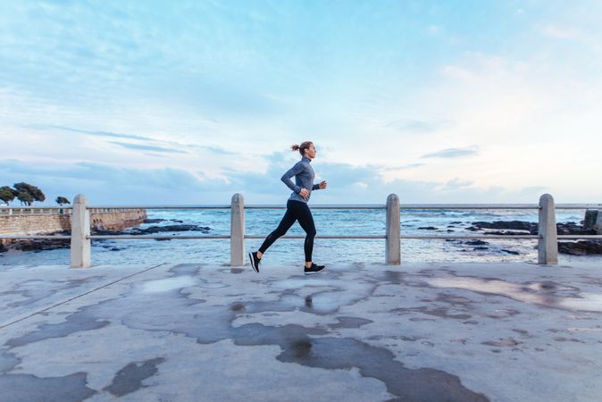 Woman athlete running outdoors along the sea