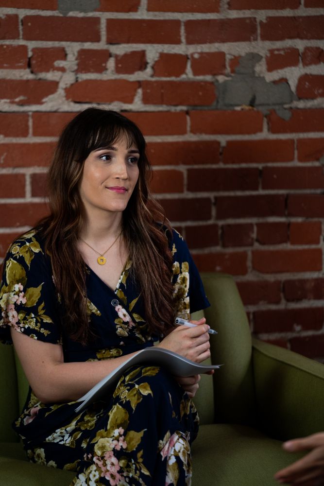 Transgender woman in floral dress discussing notes in a casual office