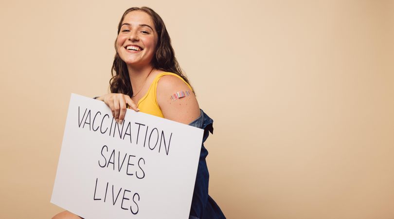 Beautiful young woman holding a banner with "vaccination saves lives" slogan