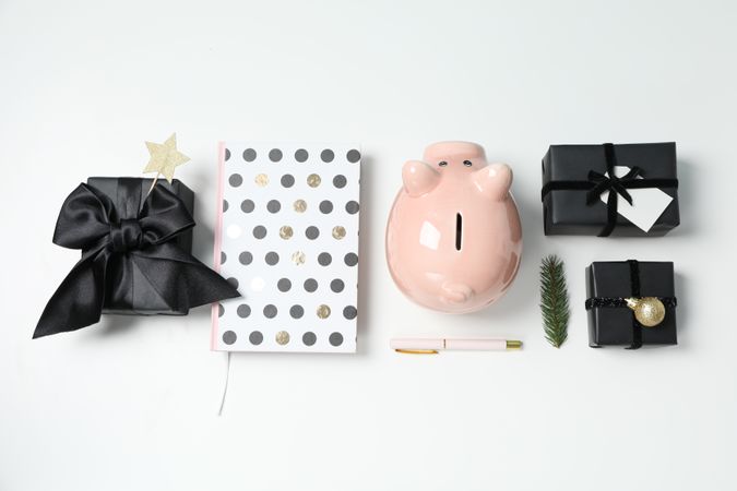 Piggy bank, gift boxes and notepads on light background, top view