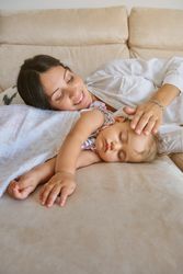 Happy woman with kid lying on sofa