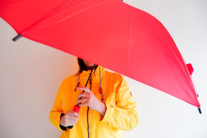 Person in yellow jacket holding red umbrella