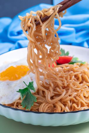 A plate of noodles with an egg and tomato on top