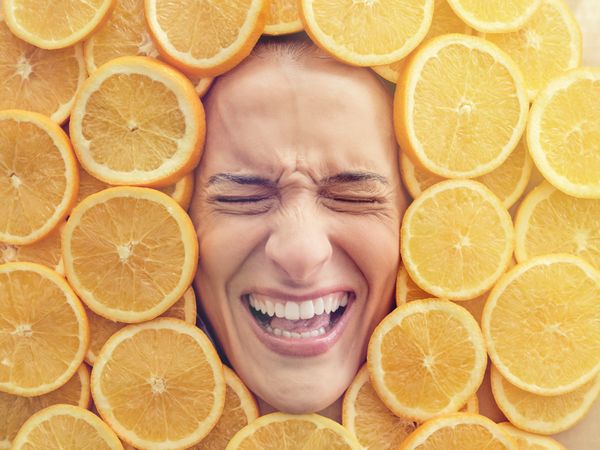 Discontent woman immersed in pile of cut oranges