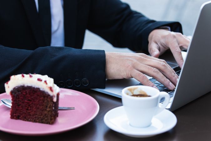Anonymous male entrepreneur in suit working in cafe