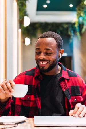 Smiling Black man with cup of coffee in cafe