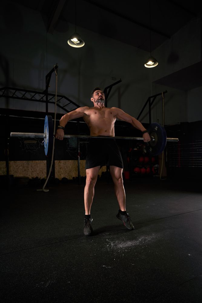 Strong sportsman lifting barbell during training in gym