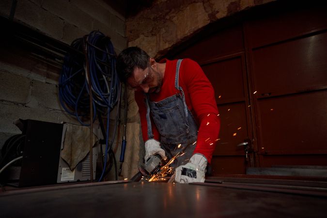 Focused craftsman cutting metal in workshop