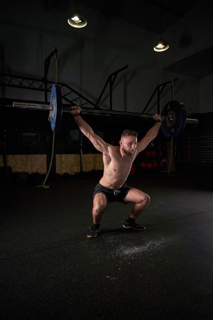 Strong sportsman doing weightlifting exercise with barbell