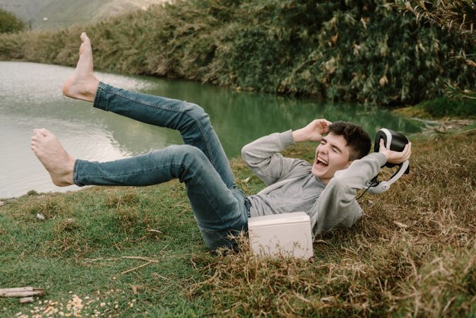 Young teenager with virtual reality glasses laughing outdoors