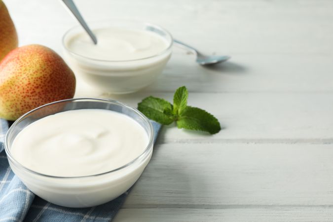 Composition with cream yogurts and fruits on light background, space for text