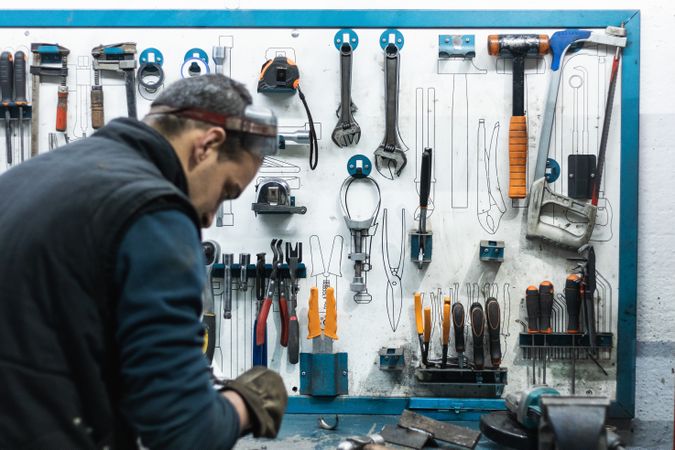 Professional mechanic using spanner while assembling vehicle engine details at workbench