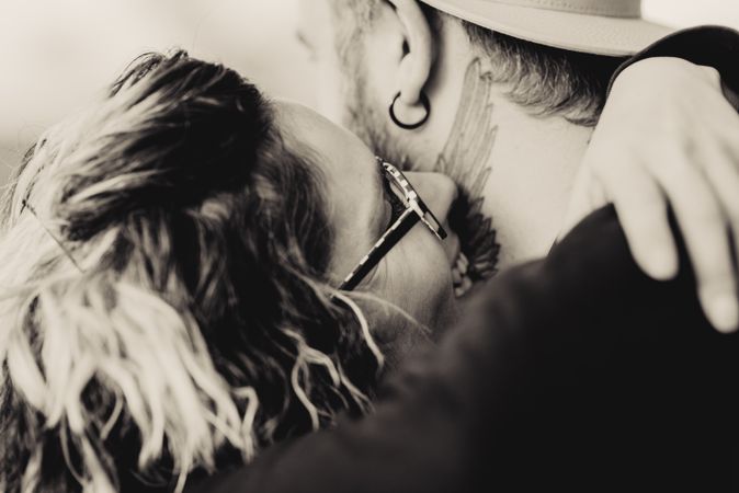 Happy couple hugging and kissing near tree in park
