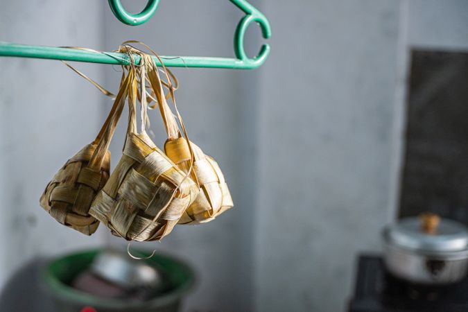 Cooked ketupat hanging on a wooden rack to keep fresh and dry