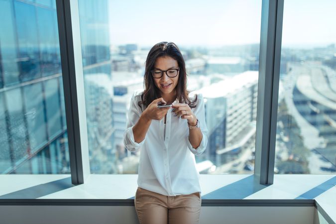 Woman wearing eyeglasses using mobile phone for business communication