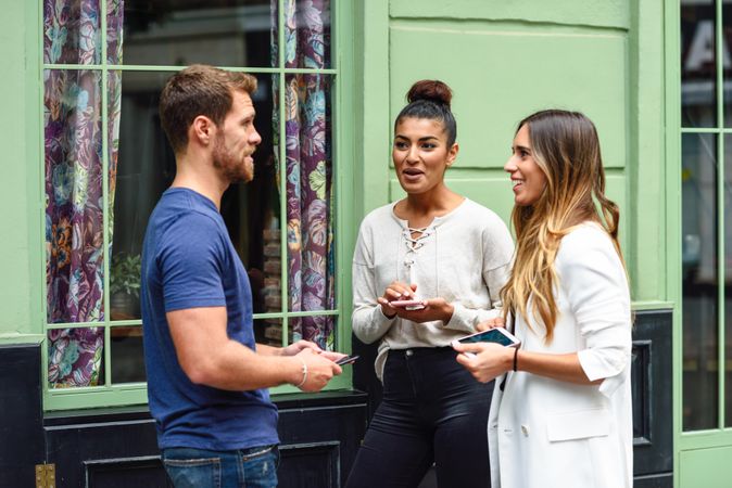 Multiracial group of friends next to green wall outside