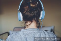 Back view of young woman wearing headphone indoor 5RXP2b