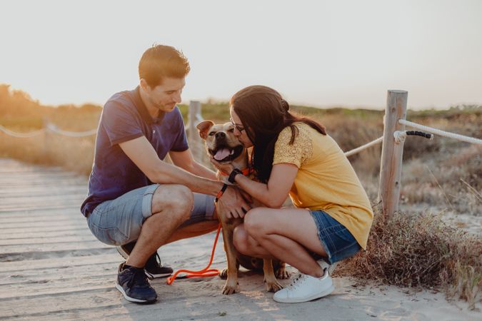 Happy adult couple petting dog at countryside