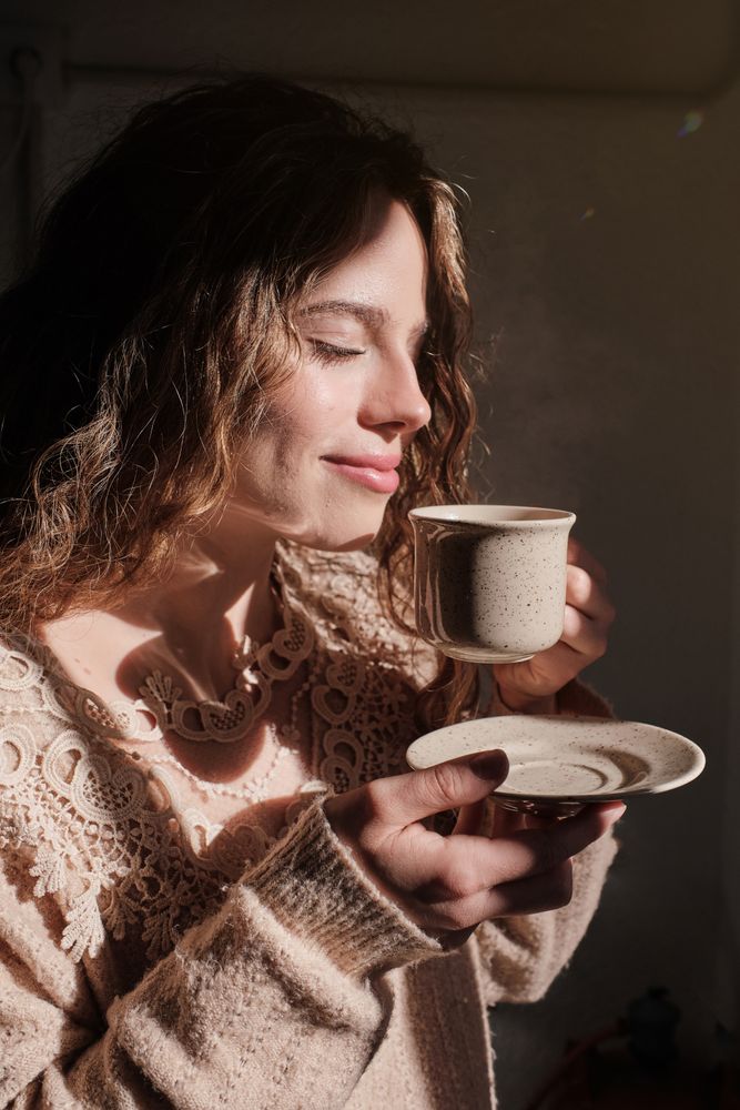 Young woman smelling aromatic cup of coffee