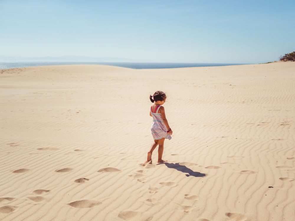 Cute little girl playing with sand at beach