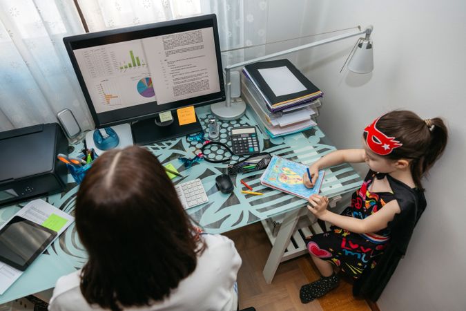 Woman teleworking with her daughter drawing