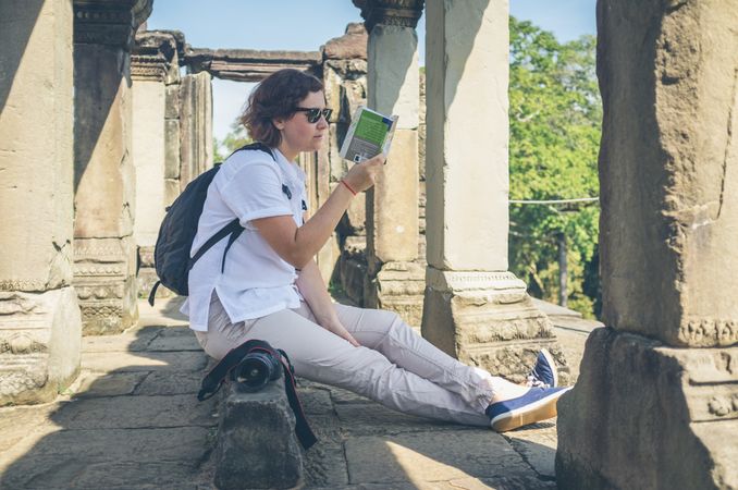 Female tourist reading guidebook in ruins