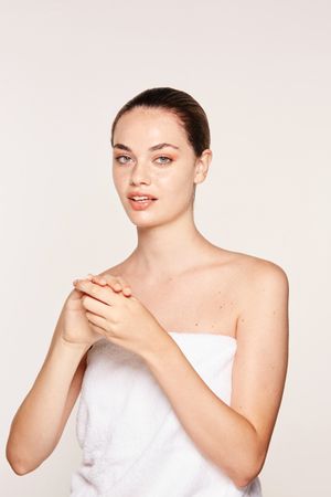Delighted female applying recovery cream on hands
