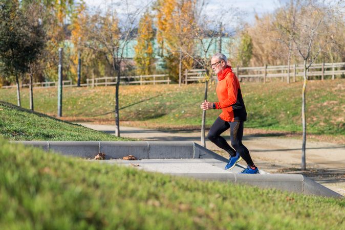 Side view of older male approaching stairs in park during workout