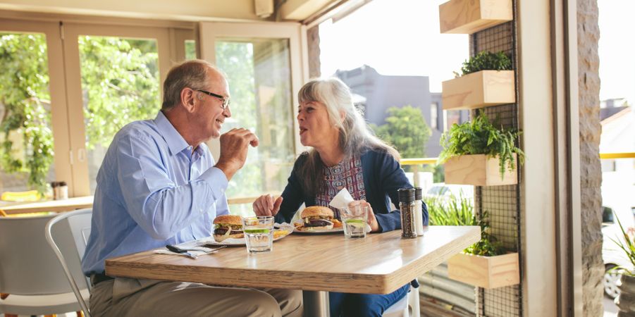 Couple enjoying eating burgers together at a cafe
