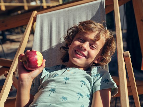 Happy boy eating apple on terrace
