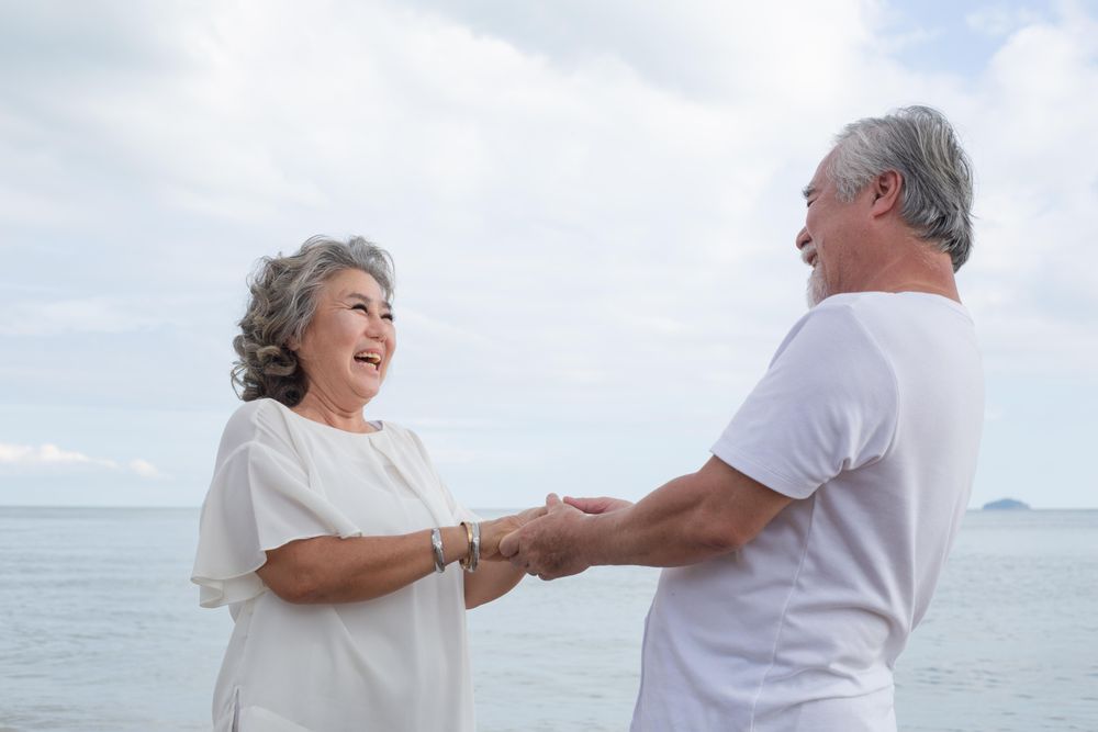 Mature Asian couple facing each other at the beach
