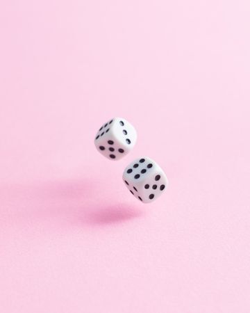 Dice falling over pink background