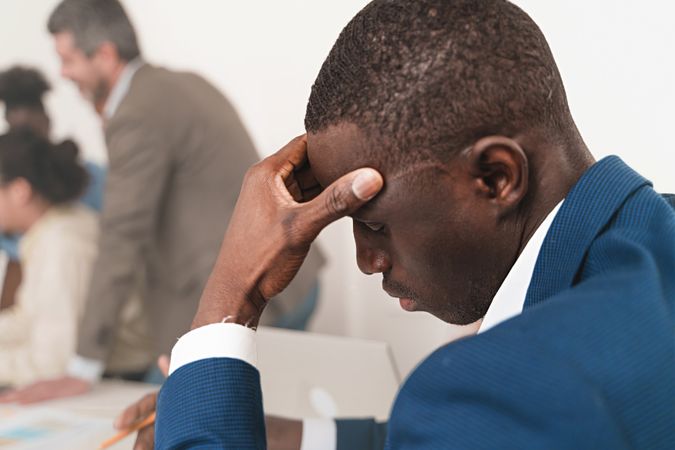 Stressed Black businessman in the office with a headache or concern
