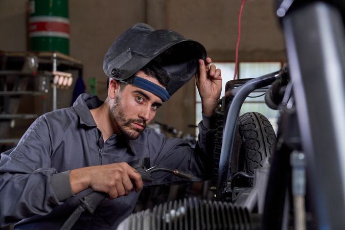 Focused mechanic working with welding machine in garage