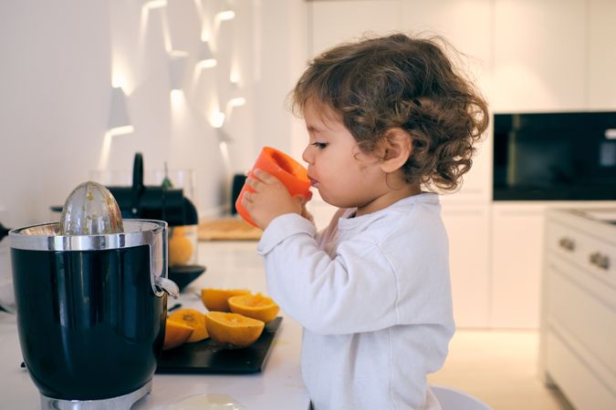 Little boy drinking fresh juice in kitchen