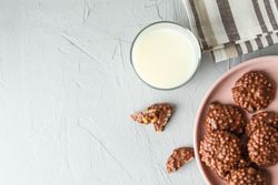 Plate with chocolate cookies and glass of milk on grey table, space for text