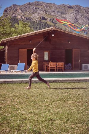 Boy running with kite at house
