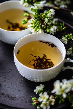 Green tea in cups with fragrant floral garnish
