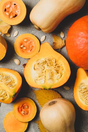 Composition with pumpkin, squash, seeds and leaves on gray background