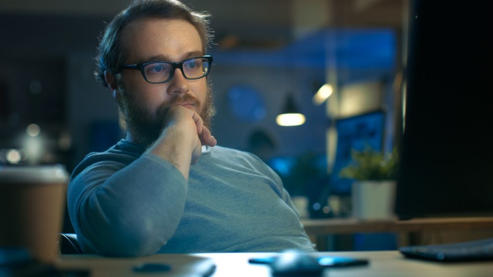 Focused Young Man Sits at His Desk and Thinks on a Problem Solution.