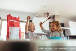 Cute little boy and girl holding whisk and spatula having fun while cooking in the kitchen 47eqk0