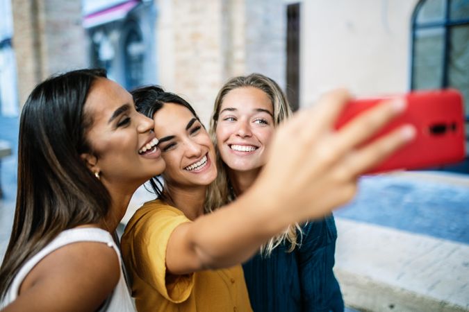 Diverse female friends taking selfie outside and smiling